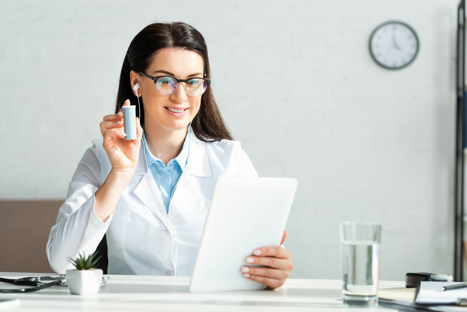 cheerful doctor showing pills to patient on online consultation on digital tablet in office